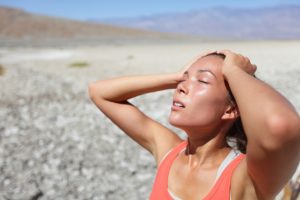 Desert woman thirsty dehydrated in Death Valley. Dehydration, overheating, thirst and heat stroke concept image with girl in desert nature.